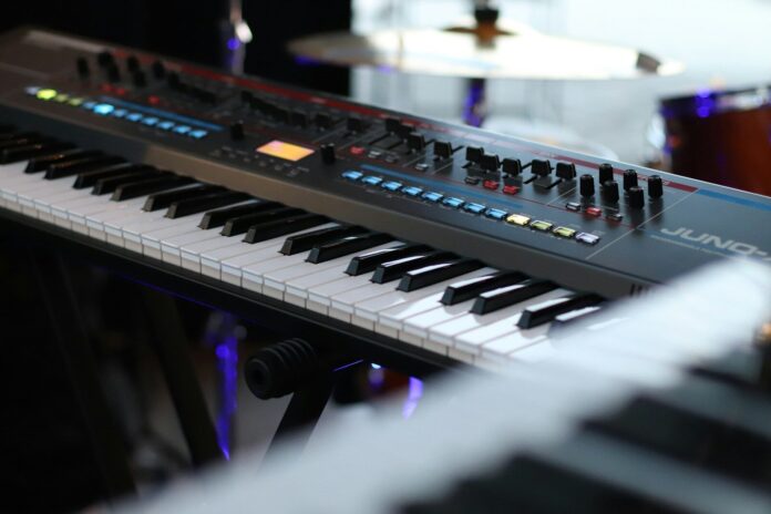 A close up of a keyboard with a drum in the background